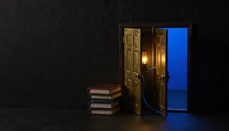 Miniature night diorama: two open brass doors over a stack of ledgers with one cobalt cable threaded through both.
